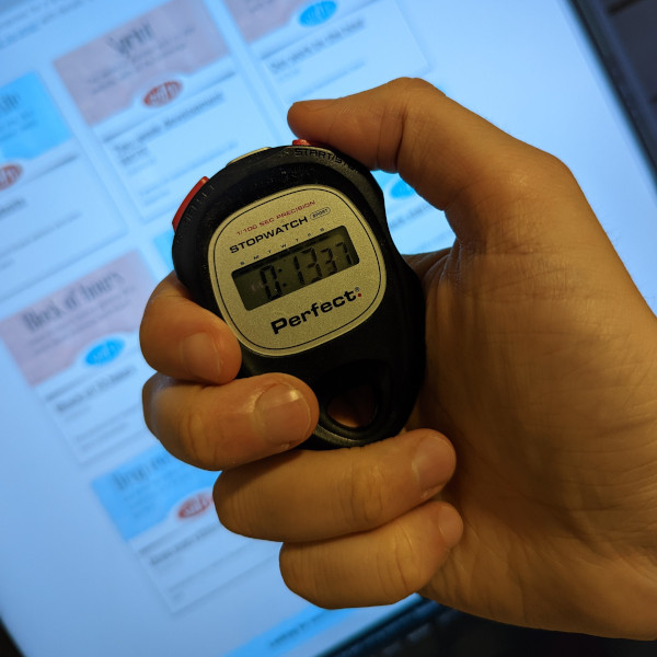 A hand controlling a stopwatch in front of a computer screen